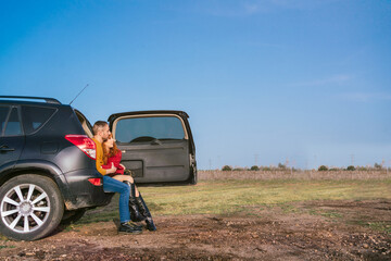 Caucasian couple sitting in a trunk of a car in a field