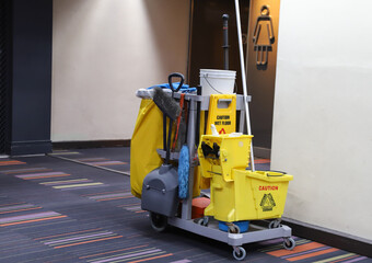 Closeup of janitorial, cleaning equipment and tools for floor cleaning in-front of rest room at airport terminal.