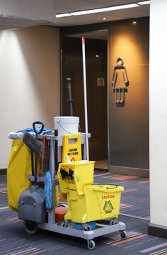 Closeup of janitorial, cleaning equipment and tools for floor cleaning in-front of rest room at airport terminal. Vertical view.