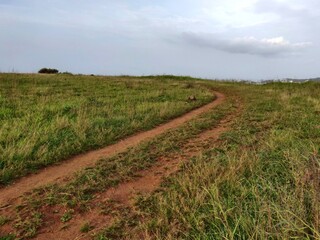 Fototapeta na wymiar An old earthen road path running beyond the hills