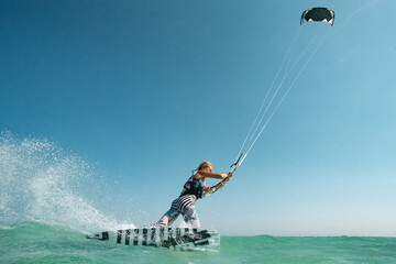 Kite surfer woman rides with kiteboard  in transition