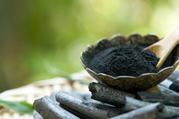 Bamboo charcoal ,green leaves and powder isolated on nature background.