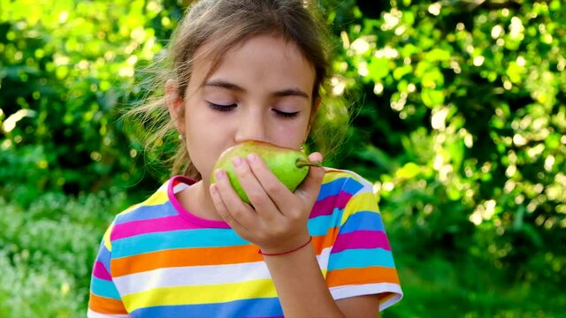 The child eats a pear in the garden. Selective focus.