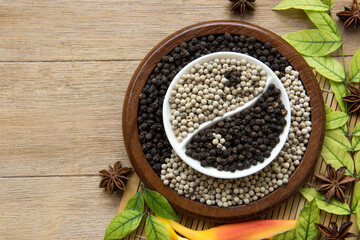 Black and white pepper arranged yin yang shape isolated on white on an old wooden background.top view,flat lay.