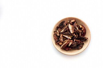 Pieces of dried boletus edulis mushroom in a bowl. Raw organic food for vegetarian or vegan diet isolated on white background. Selective focus on the details, blurred background.