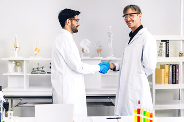Professional two scientist man research and working doing a chemical experiment while making analyzing and mixing liquid in test tube.Young science man dropping sample chemical on glass at laboratory