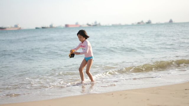 Asian Chinese girl daughter child playing with plastic toy excavator by the sea