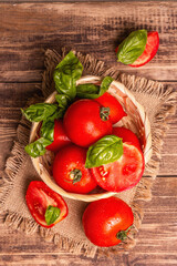 Ripe red tomatoes with fresh basil in a wicker basket
