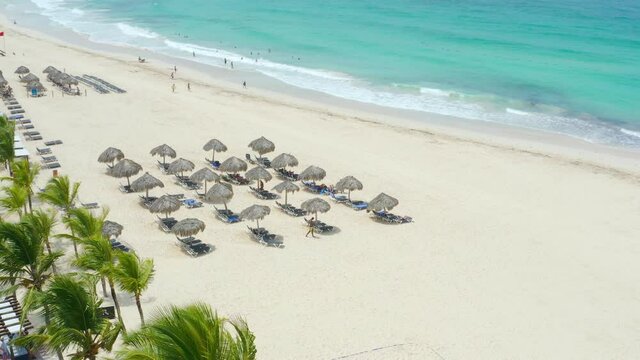 Sunny thatched umbrellas and sun loungers on a white-sand Caribbean beach.