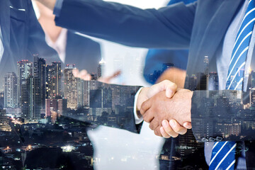 Double exposure of business handshake and city night. Business people shaking hands in the office. Finishing successful meeting.