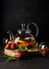 selective focus, freshly brewed tea in a transparent teapot, with fruits and fresh berries. leaf...