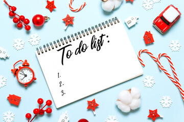 Fototapeta na wymiar To do list in notepad with christmas decorations on blue background. Flat lay, top view, copy space. New year winter holiday xmas concept