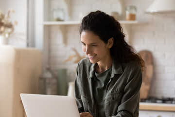 Smiling young attractive hispanic latina woman using computer software applications, sitting at...