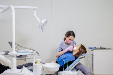 Female dentist checking up patient teeth at dental clinic office. Medicine, dentistry concept....