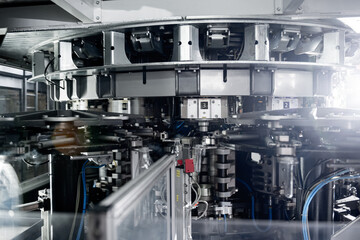 Automatic filling machine pours water into plastic PET bottles at modern beverage plant.