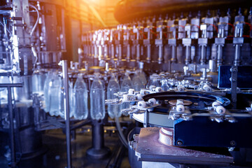 Automatic filling machine pours water into plastic PET bottles at modern beverage plant.