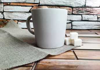 an ordinary gray mug with three sugar cubes on a napkin on a brick background