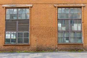 Large old dilapidated red brick house with large dilapidated windows. An old abandoned factory building.