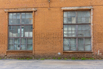 Large old dilapidated red brick house with large dilapidated windows. An old abandoned factory building.