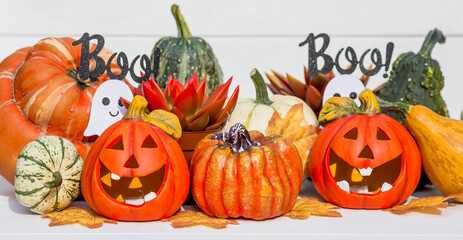 Happy Halloween! Pumpkin Jack on the table. Lantern with a carved smile and different attributes of the holiday on a light background.A copy of the place for the text.