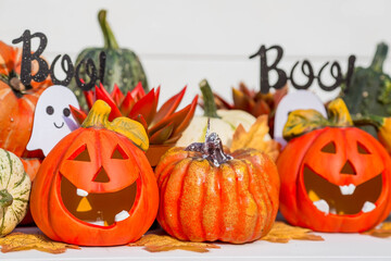 Happy Halloween! Pumpkin Jack on the table. Lantern with a carved smile and different attributes of the holiday on a light background.A copy of the place for the text.