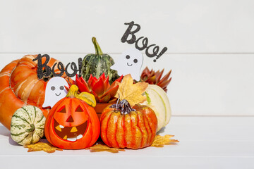 Happy Halloween! Pumpkin Jack on the table. Lantern with a carved smile and different attributes of the holiday on a light background.A copy of the place for the text.