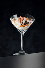 Cocktail glass filled with colorful medical pills. Drug dependency, overuse, healthcare industry medical treatment
