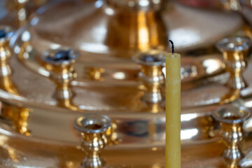 Fototapeta na wymiar Extinguished candles on the background of a golden candlestick in the Orthodox church. The interior of the church. A place for prayer and repentance.