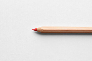 Red wooden crayon pencil on white background. Close up macro view