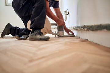 Repairman restoring parquet with a sanding machine.
