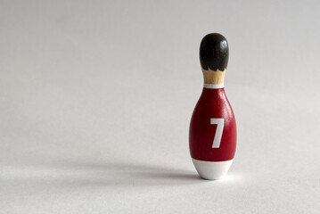 rearview of a wooden puppet in the shape of a bowling pin with a number seven shirt