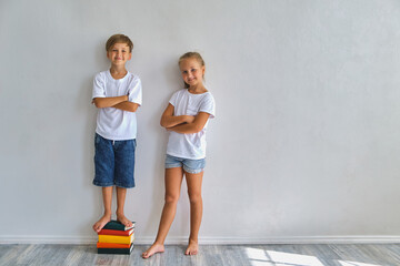 Little girl and boy measuring their height - obrazy, fototapety, plakaty