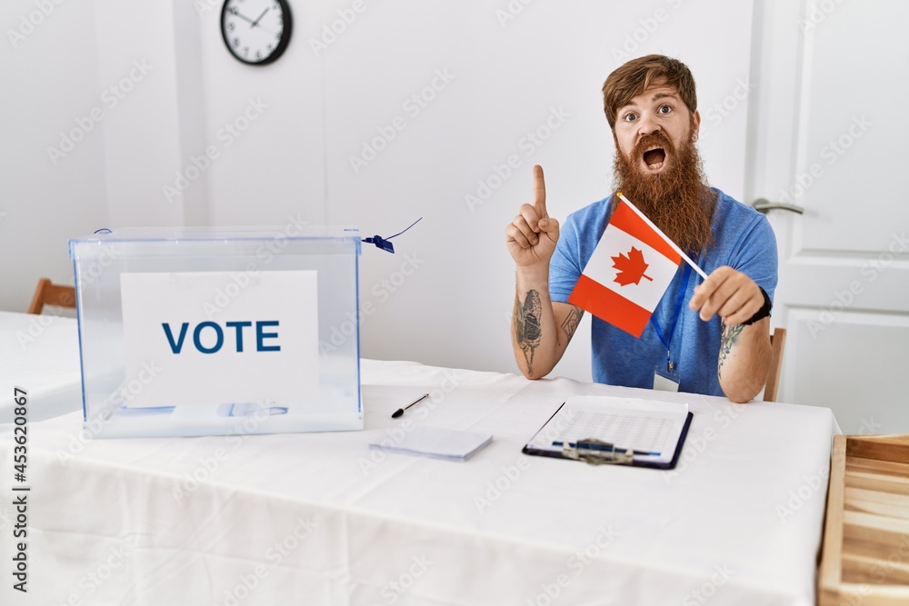 Sticker Caucasian man with long beard at political campaign election holding canada flag surprised with an idea or question pointing finger with happy face, number one