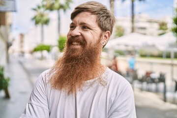 Young redhead man smiling happy standing at the city.