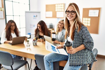 Fototapeta premium Young businesswoman smiling happy drinking coffee while partners work at the office.