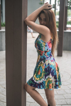 Lovely asian woman in casual colourful dress standing outdoors. Long hair. Nice posture. High quality photo 