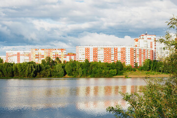 Obraz premium City landscape view from the river bank. A modern residential area with multi-storey buildings.