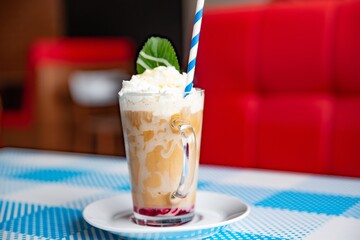 Iced caramel latte coffee in a tall glass with chocolate syrup and whipped cream.