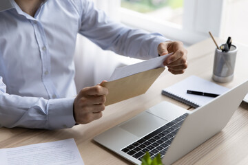 Hands of businessman opening envelope with white paper, taking out document for reading. Business...