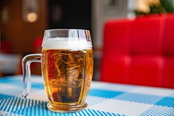 A mug of cold beer on a table in a pizzeria or restaurant.