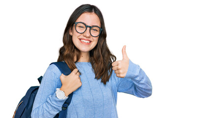 Young beautiful girl wearing student backpack smiling happy and positive, thumb up doing excellent and approval sign