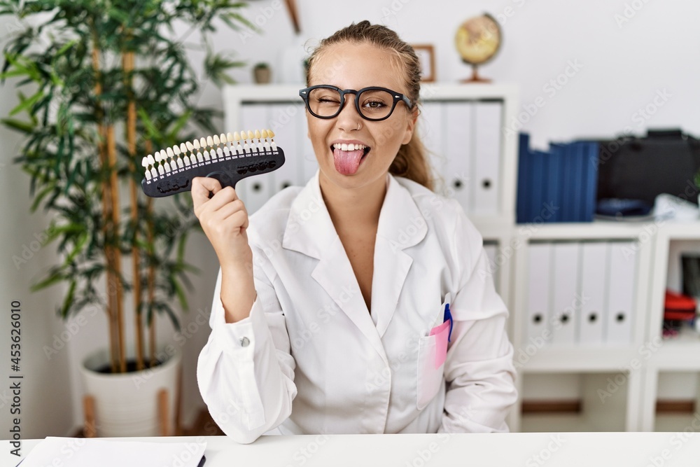 Sticker Young caucasian woman holding teeth whitening palette sticking tongue out happy with funny expression. emotion concept.