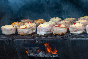 Cooking meatballs covered with bacon on the grill