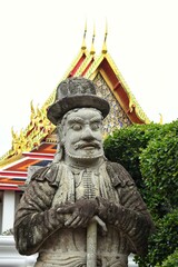 Obraz premium Chinese giants figure in european clothes beside a gate in Wat Pho also spelled Wat Po, is a Buddhist temple in Bangkok, Thailand.