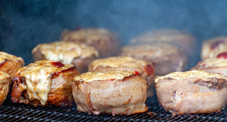 Cooking meatballs covered with bacon on the grill
