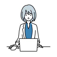 デスクで座ってPCを使っているジャケットの女性