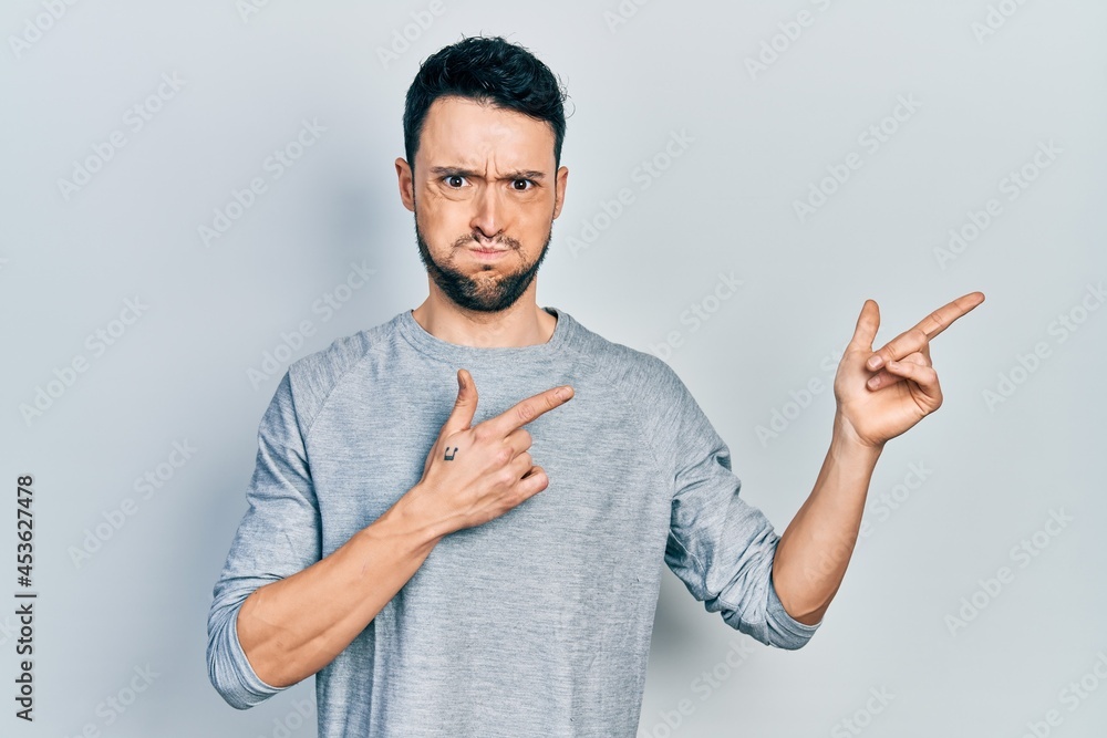 Poster Young hispanic man pointing with fingers to the side puffing cheeks with funny face. mouth inflated with air, catching air.