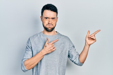 Young hispanic man pointing with fingers to the side puffing cheeks with funny face. mouth inflated...