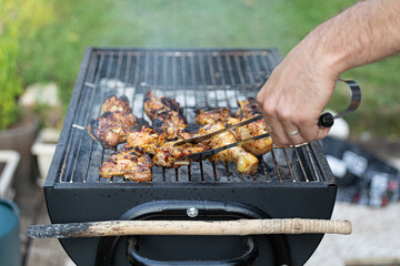 Man's hand cooking meat on a grill