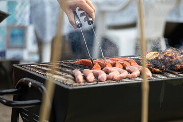 Man's hand cooking meat on a grill